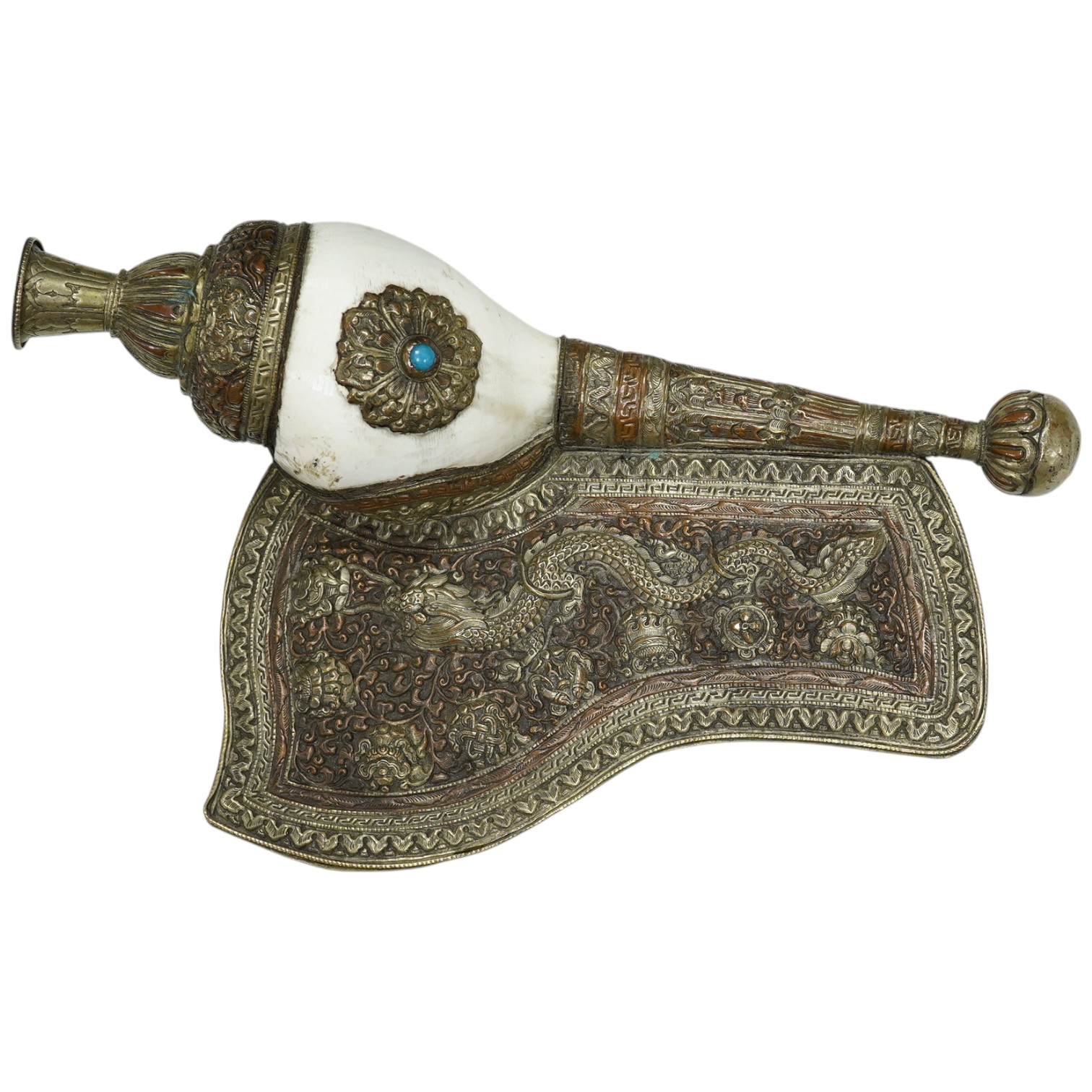 A Tibetan repoussé work cowrie shell trumpet, early 20th century, set with a cabochon, 37cm high. Condition - fair to good